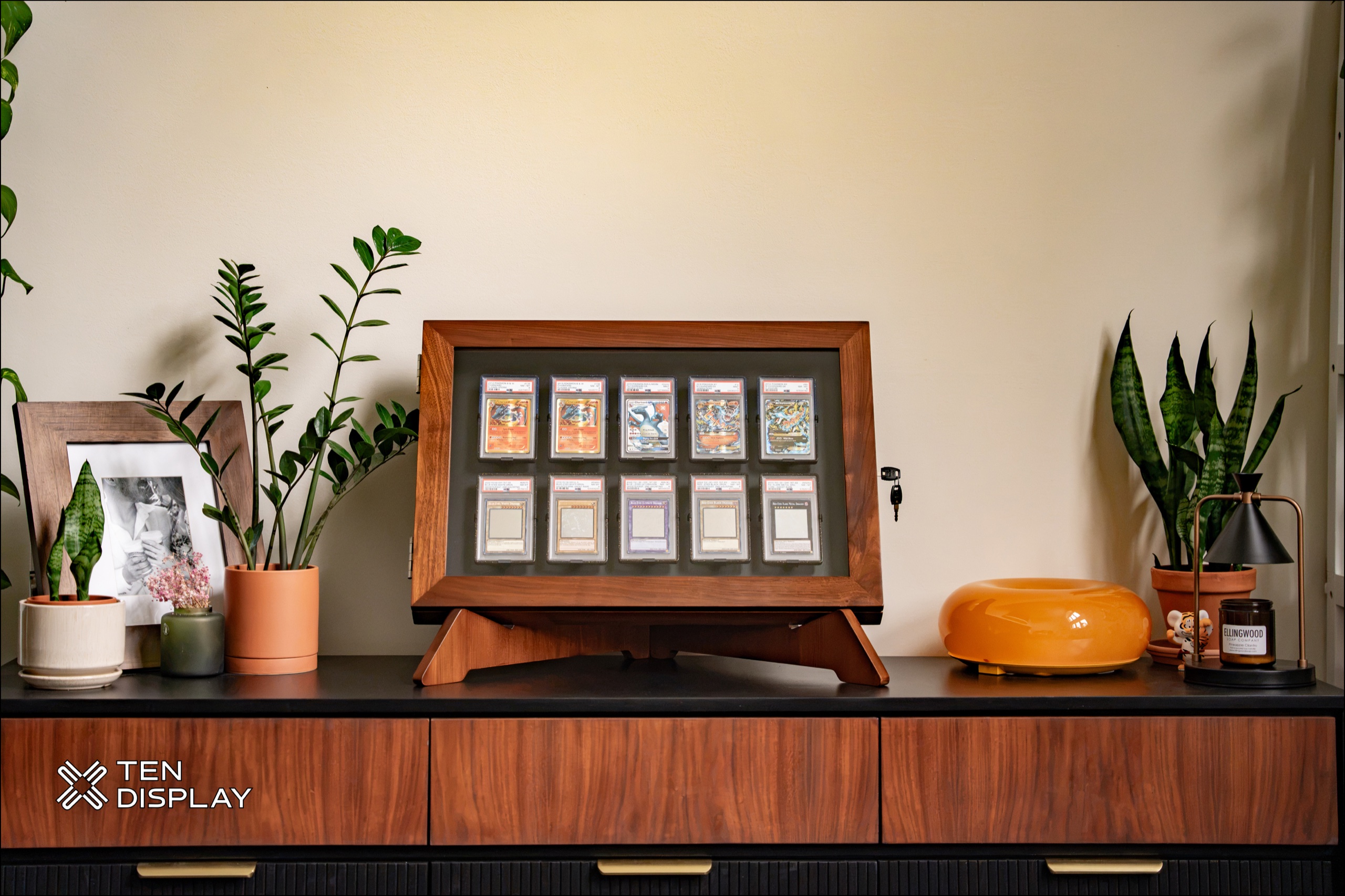 Ten Display walnut Launch Edition on its finish-matched stand atop a console — real hardwood frame with graded cards visible